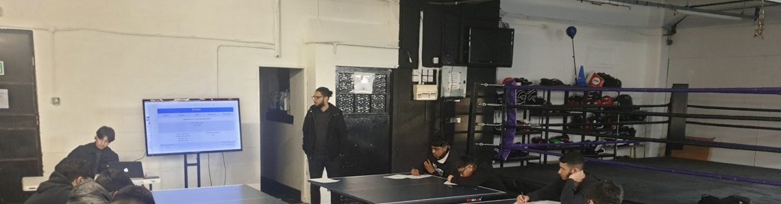 Students studying at table tennis tables inside the gym for Homework Club